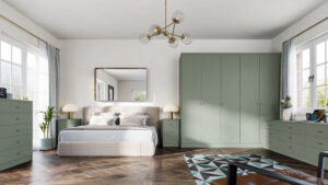 A modern bedroom with a king-sized bed, pale green cabinetry, and a geometric rug. Two large windows allow natural light to illuminate the space. A contemporary chandelier hangs from the ceiling, and a large mirror is above the beds headboard.